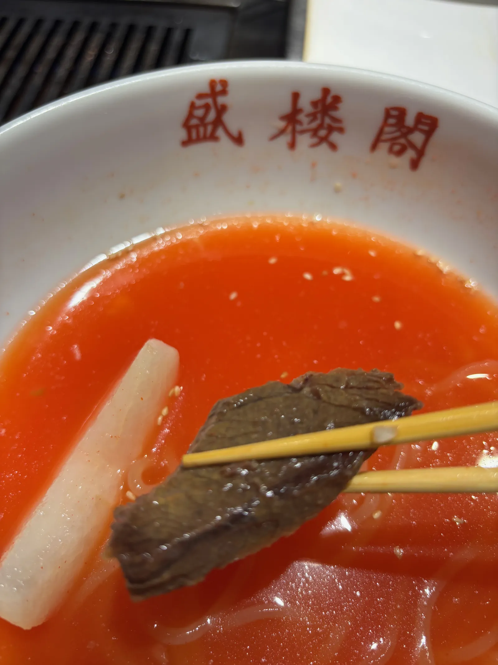 盛楼閣の冷麺に入っていたチャーシューを箸でつまんだアップ写真