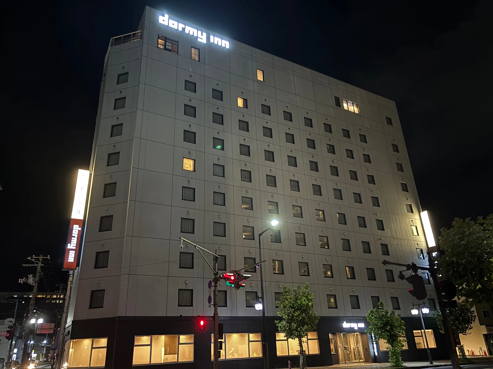 夜のドーミーイン盛岡の外観。ビル全体が明るく照明され、1階入口に看板が出ている